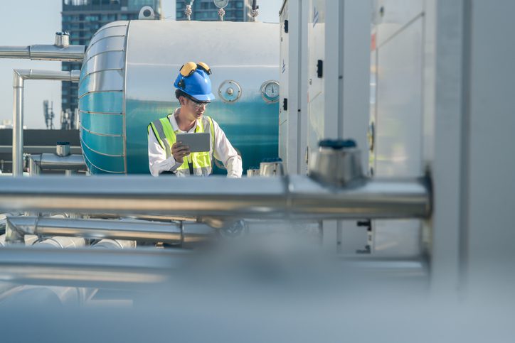 Technical professional evaluating air conditioning units on top of an urban high-rise. Technical professional evaluating air conditioning units on top of an urban high-rise.